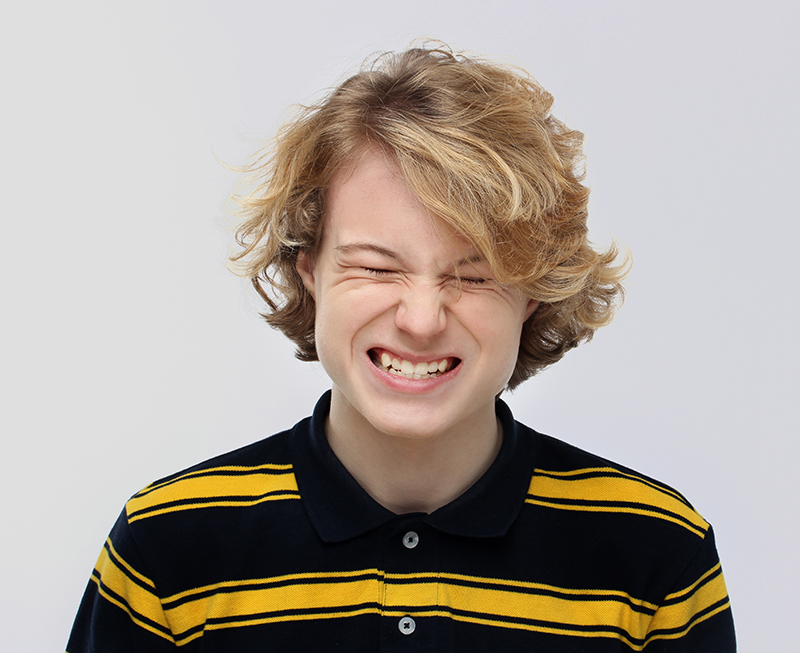 Blonde teenage boy grinding teeth in extreme rage